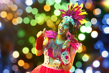 Image showing Beautiful young woman in carnival mask and masquerade costume in colorful lights