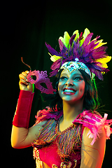 Image showing Beautiful young woman in carnival mask and masquerade costume in colorful lights