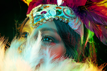 Image showing Beautiful young woman in carnival mask and masquerade costume in colorful lights