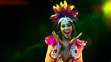 Image showing Beautiful young woman in carnival mask and masquerade costume in colorful lights, flyer