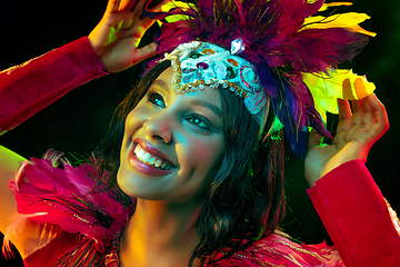 Image showing Beautiful young woman in carnival mask and masquerade costume in colorful lights