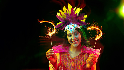 Image showing Beautiful young woman in carnival mask and masquerade costume in colorful lights, flyer