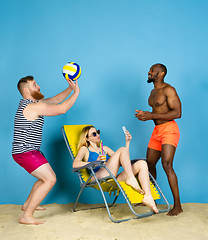 Image showing Happy young friends resting on blue studio background