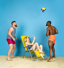 Image showing Happy young friends resting on blue studio background
