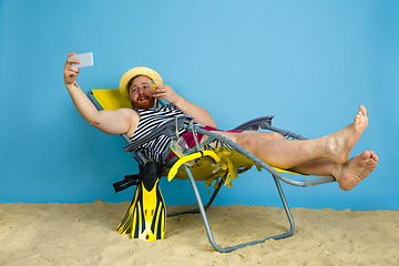 Image showing Happy young man resting on blue studio background