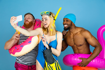 Image showing Happy young friends resting on blue studio background