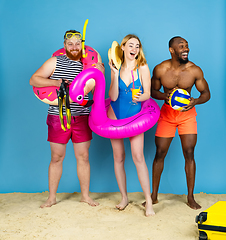 Image showing Happy young friends resting on blue studio background