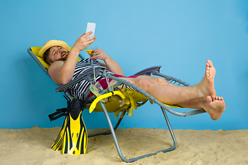 Image showing Happy young man resting on blue studio background