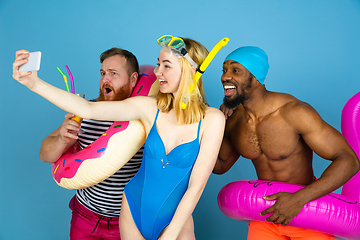 Image showing Happy young friends resting on blue studio background