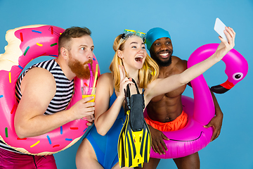 Image showing Happy young friends resting on blue studio background