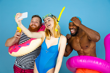 Image showing Happy young friends resting on blue studio background