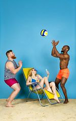 Image showing Happy young friends resting on blue studio background