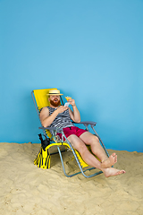 Image showing Happy young man resting on blue studio background