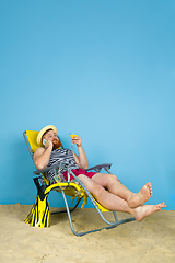 Image showing Happy young man resting on blue studio background