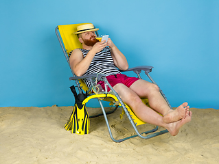 Image showing Happy young man resting on blue studio background