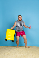 Image showing Happy young man resting on blue studio background