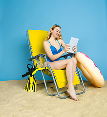 Image showing Happy young woman resting on blue studio background