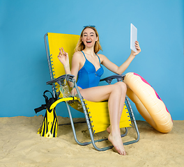 Image showing Happy young woman resting on blue studio background