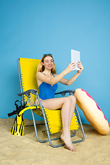 Image showing Happy young woman resting on blue studio background