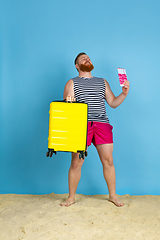 Image showing Happy young man resting on blue studio background