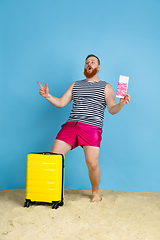 Image showing Happy young man resting on blue studio background