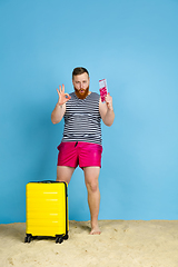 Image showing Happy young man resting on blue studio background