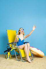 Image showing Happy young woman resting on blue studio background