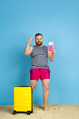 Image showing Happy young man resting on blue studio background