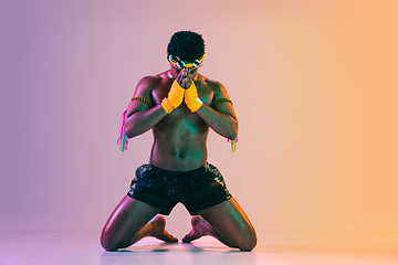 Image showing Muay thai. Young man exercising thai boxing on gradient background