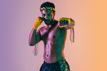 Image showing Muay thai. Young man exercising thai boxing on gradient background