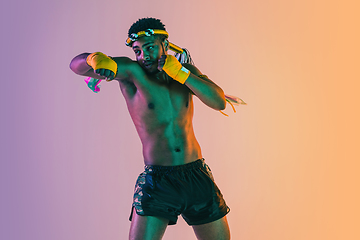 Image showing Muay thai. Young man exercising thai boxing on gradient background