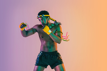 Image showing Muay thai. Young man exercising thai boxing on gradient background