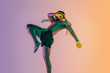 Image showing Muay thai. Young man exercising thai boxing on gradient background