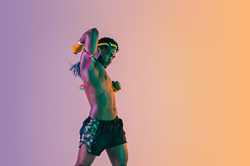 Image showing Muay thai. Young man exercising thai boxing on gradient background