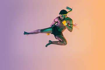 Image showing Muay thai. Young man exercising thai boxing on gradient background