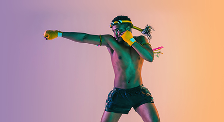 Image showing Muay thai. Young man exercising thai boxing on gradient background