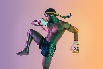 Image showing Muay thai. Young man exercising thai boxing on gradient background