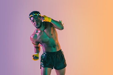 Image showing Muay thai. Young man exercising thai boxing on gradient background