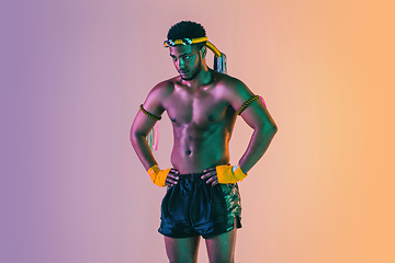 Image showing Muay thai. Young man exercising thai boxing on gradient background