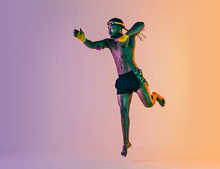 Image showing Muay thai. Young man exercising thai boxing on gradient background