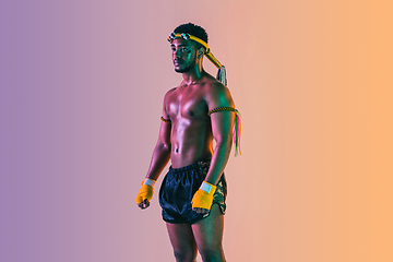 Image showing Muay thai. Young man exercising thai boxing on gradient background