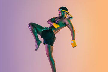 Image showing Muay thai. Young man exercising thai boxing on gradient background