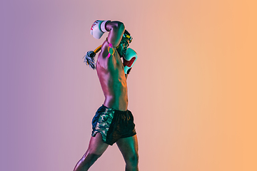 Image showing Muay thai. Young man exercising thai boxing on gradient background