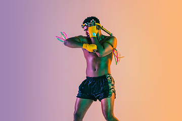 Image showing Muay thai. Young man exercising thai boxing on gradient background