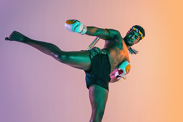 Image showing Muay thai. Young man exercising thai boxing on gradient background