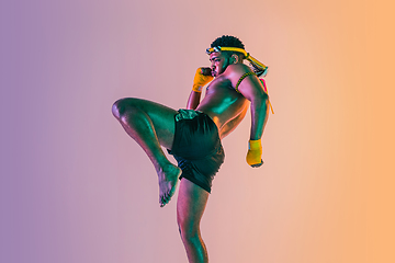 Image showing Muay thai. Young man exercising thai boxing on gradient background