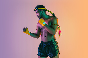 Image showing Muay thai. Young man exercising thai boxing on gradient background