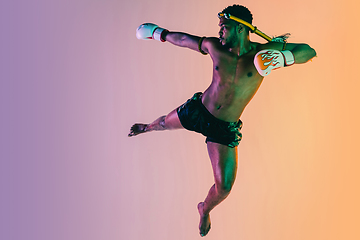 Image showing Muay thai. Young man exercising thai boxing on gradient background