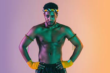 Image showing Muay thai. Young man exercising thai boxing on gradient background