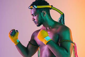 Image showing Muay thai. Young man exercising thai boxing on gradient background